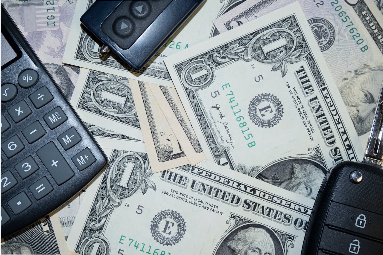 services-04 An arrangement of US dollar bills, car keys, and a calculator representing finance and investment concepts.