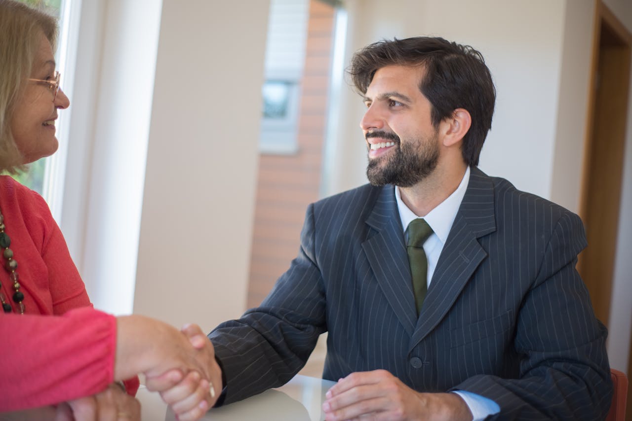 journey Professional real estate agent sealing a deal with a senior client indoors through a handshake.